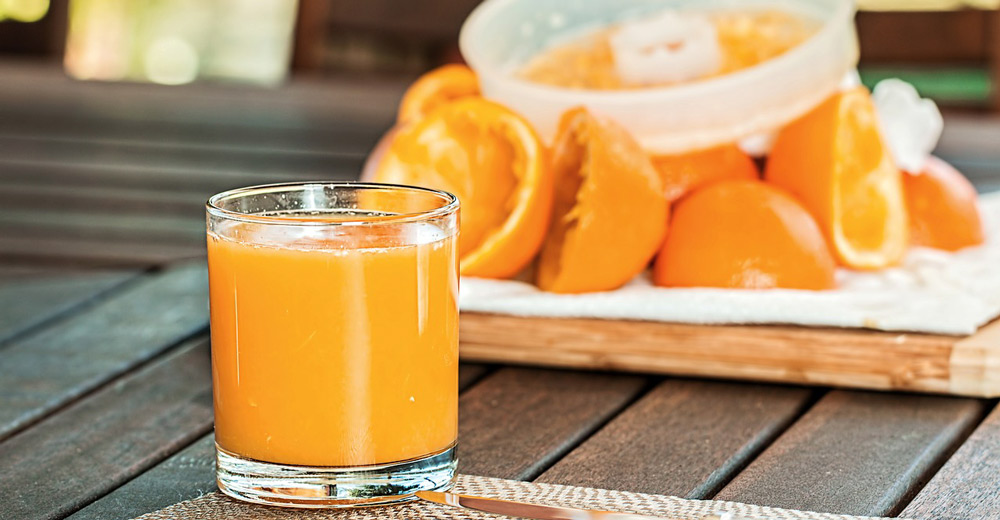 A fresh cup of orange juice on a table.