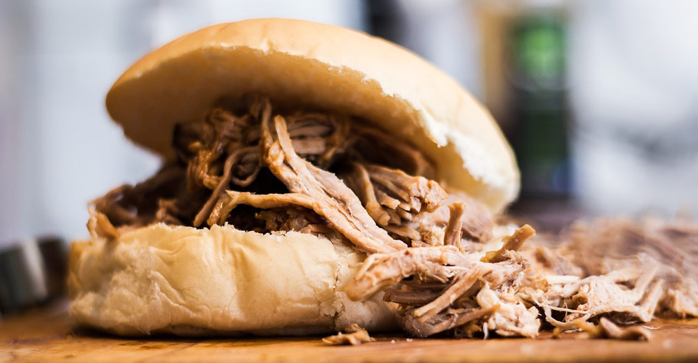 A pull pork sandwich on a cutting board.