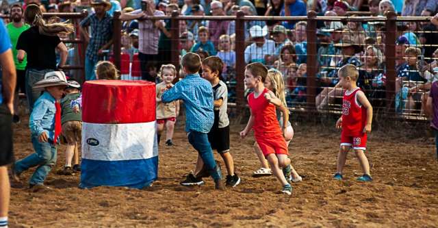 Little kids participating in a run in between rodeo contestants.