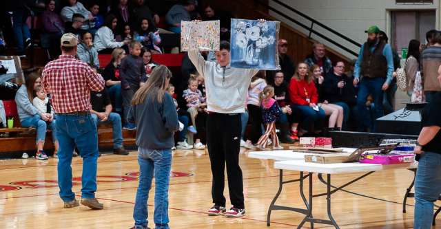 COUCH, MO – JANUARY 14: Couch basketball players holding up pictures for the benefit auction for Brian Hinton during the high school basketball game between the Alton Comets and Couch Indians on January 14, 2025 at the Couch High School Gym in Couch, Missouri. (Photo by Amanda Thomas/AltonMo.com)